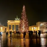 Nocny jarmark bożonarodzeniowy w Berlinie. Brama Brandenburska i rozświetlona choinka tworzą magiczną atmosferę.
