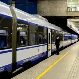 Konduktor czeka przy drzwiach nowoczesnego pociągu PKP Intercity. Malczewski pociąg stoi na peronie, gotowy do podróży.