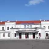 Dworzec PKP Ełk z czerwonym dachem i napisem "Dworzec Kolejowy". Obok hostel "Open Tours".