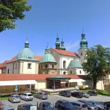 Kraków Kalwaria Zebrzydowska: barokowy zespół klasztorny z zielonymi kopułami i wieżami, otoczony parkingiem i drzewami.