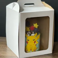 Tort z Pikachu w białym pudełku z okienkiem.