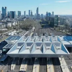 Nowoczesny dach nad peronami największego dworca w Polsce, Warszawy Centralnej, z widokiem na panoramę miasta.
