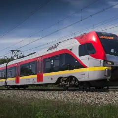 Nowy pociąg PKP Intercity "Łódź Kaliska-Kołobrzeg" pędzi po torach, mijając zielone drzewa.
