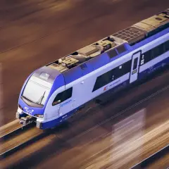 Nowoczesny pociąg IC OSTERWA pędzi po torach, tworząc rozmyte smugi światła i cienia.