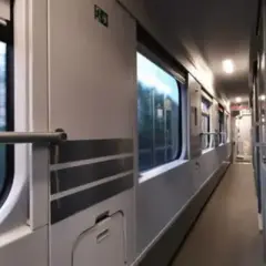 Wnętrze wagonu PKP. Podróż z Lublina do Kołobrzegu. Widok na korytarz i okna, przez które widać rozmyty krajobraz.