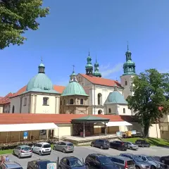 Kraków Kalwaria Zebrzydowska: barokowy zespół klasztorny z zielonymi kopułami i wieżami, otoczony parkingiem i drzewami.