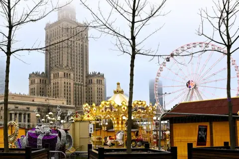 Złota karuzela i diabelski młyn na jarmarku świątecznym Warszawa. W tle Pałac Kultury i Nauki.