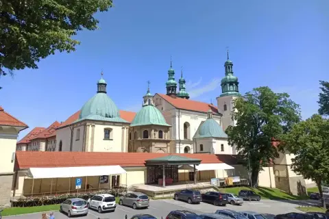 Kraków Kalwaria Zebrzydowska: barokowy zespół klasztorny z zielonymi kopułami i wieżami, otoczony parkingiem i drzewami.