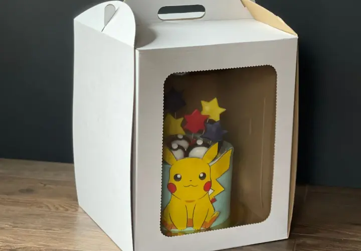 Tort z Pikachu w białym pudełku z okienkiem.
