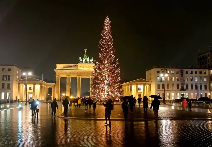 Nocny jarmark bożonarodzeniowy w Berlinie. Brama Brandenburska i rozświetlona choinka tworzą magiczną atmosferę.