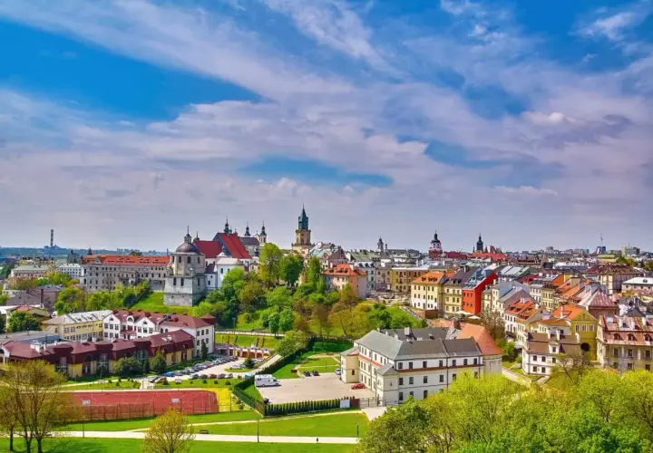 Widok na miasto z kolorowymi kamienicami i kościołami, zielonymi wzgórzami i boiskiem sportowym. Lubelszczyzna atrakcje zachwycają!