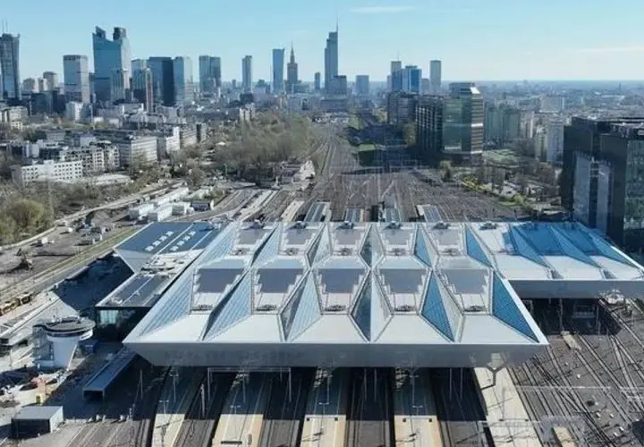 Nowoczesny dach nad peronami największego dworca w Polsce, Warszawy Centralnej, z widokiem na panoramę miasta.