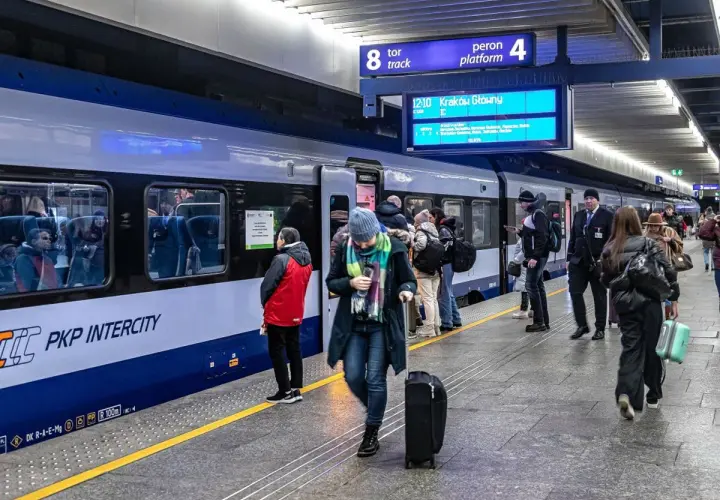 Ludzie z bagażami czekają na pociąg PKP Intercity. Na tablicy informacyjnej widnieje kierunek Kraków Główny. Może to być początek podróży z biletem kredytowym.