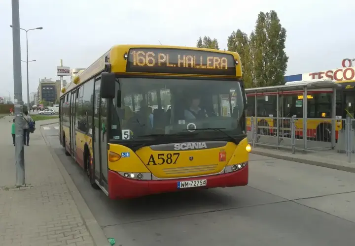 Żółty autobus linii 166 w Warszawie, z napisem "166 PL. HALLERA" na wyświetlaczu, zbliża się do przystanku.