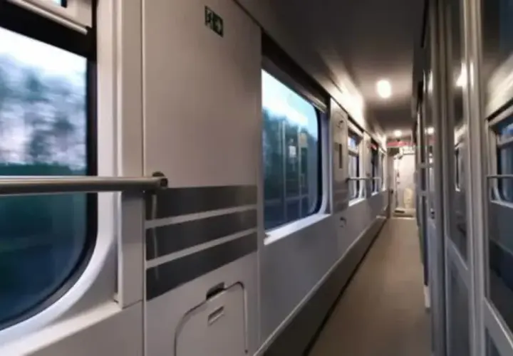 Wnętrze wagonu PKP. Podróż z Lublina do Kołobrzegu. Widok na korytarz i okna, przez które widać rozmyty krajobraz.