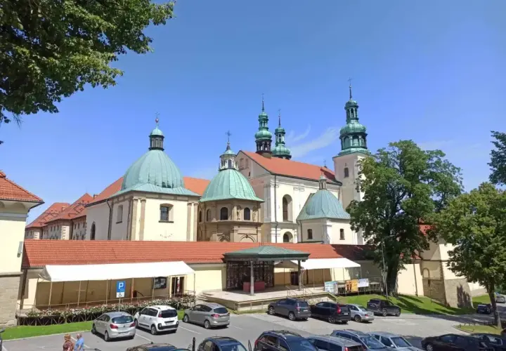 Kraków Kalwaria Zebrzydowska: barokowy zespół klasztorny z zielonymi kopułami i wieżami, otoczony parkingiem i drzewami.