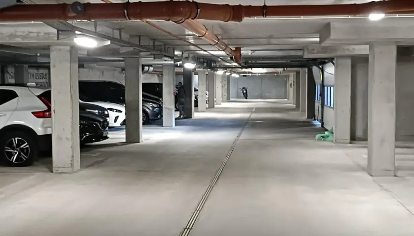 Wrocław Główny parking cennik: podziemny parking z samochodami, rurami i motocyklem w oddali.