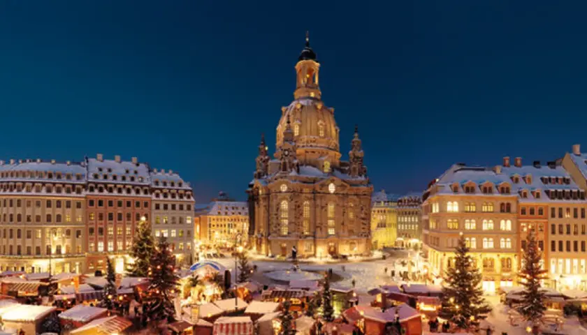 Śnieżny jarmark w Dreźnie. W tle Frauenkirche, po bokach oświetlone kamienice i choinki.
