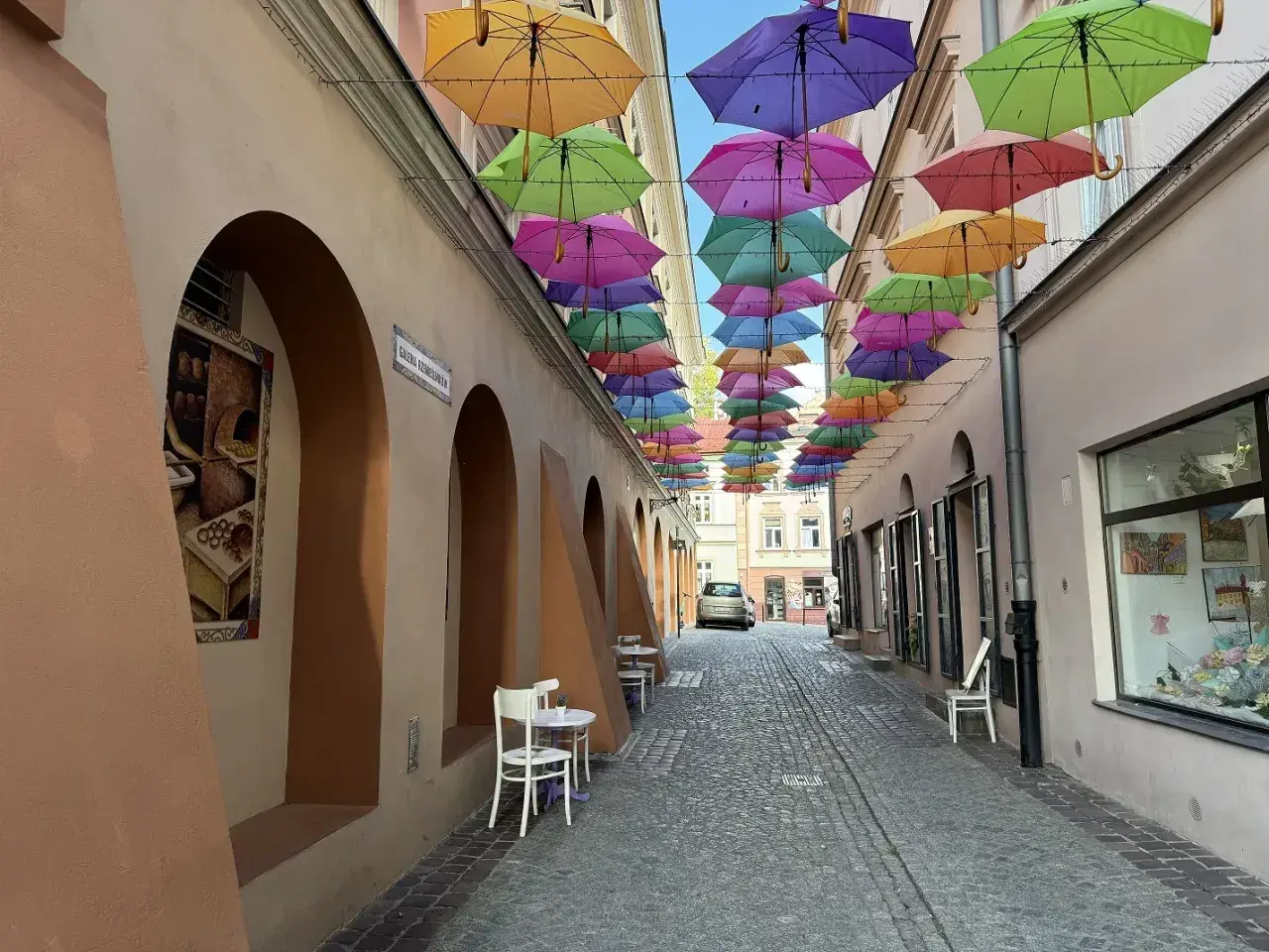 Kolorowe parasole nad brukowaną uliczką tworzą magiczną atmosferę, idealną na weekendowe atrakcje w Tarnowie.