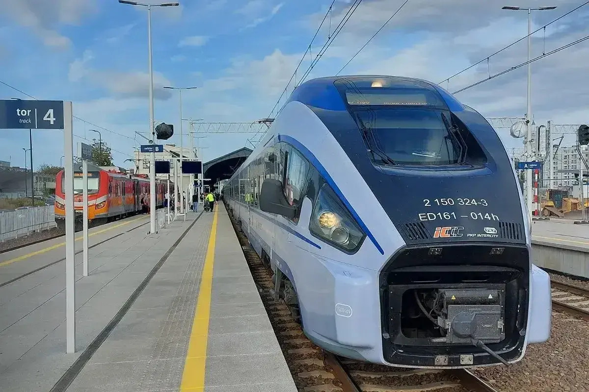 Nowoczesny pociąg Pendolino ED161 "Chrobry" na stacji. Obok stoi czerwony pociąg regionalny.