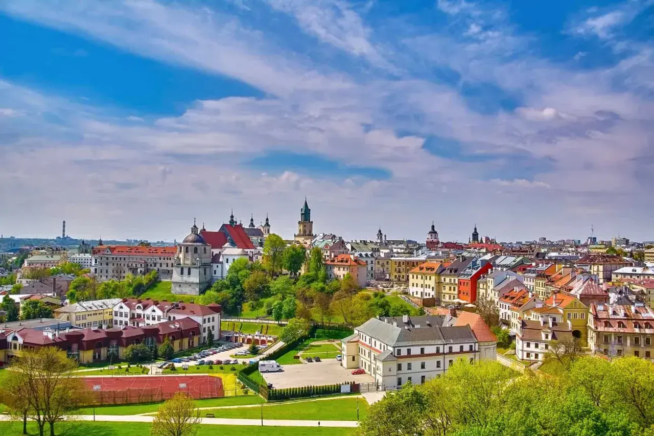 Widok na miasto z kolorowymi kamienicami i kościołami, zielonymi wzgórzami i boiskiem sportowym. Lubelszczyzna atrakcje zachwycają!