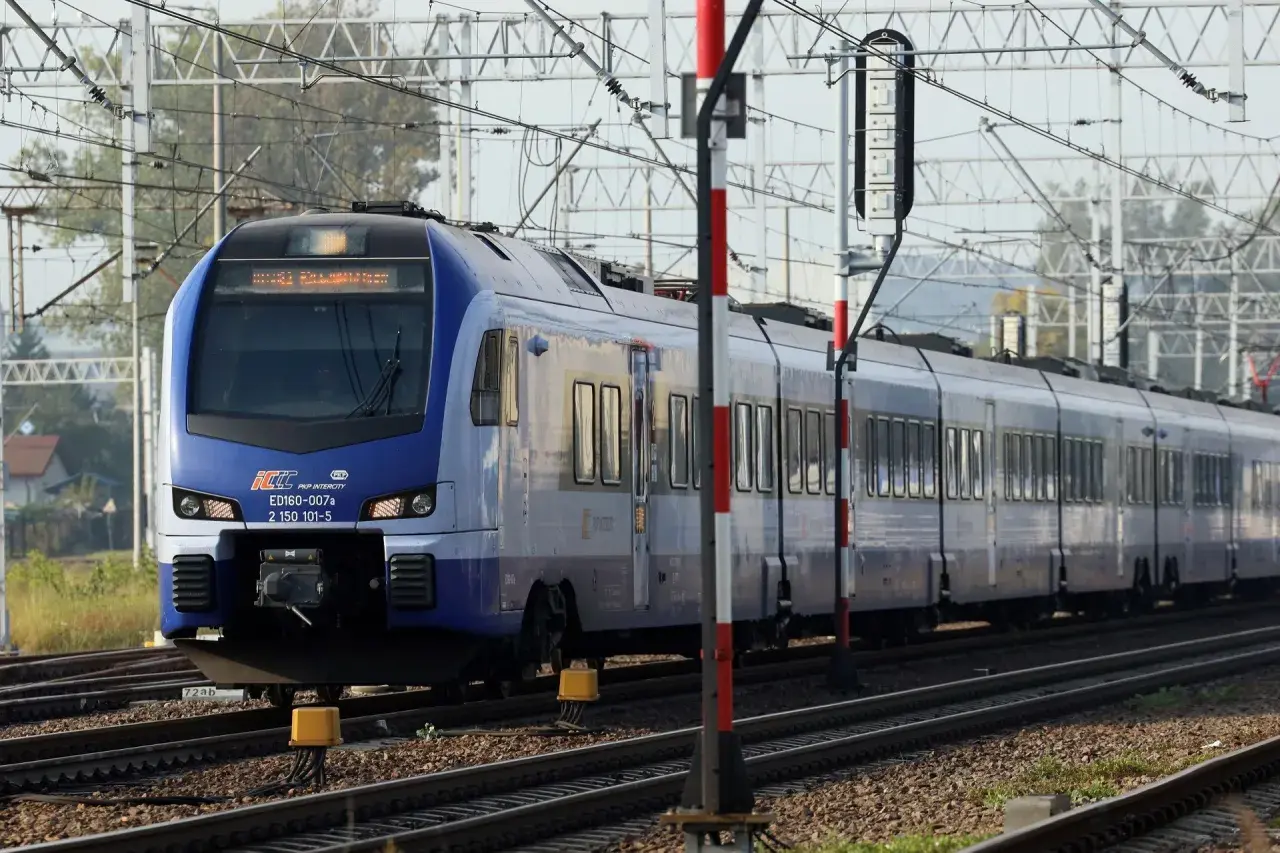 Niebieski pociąg PKP Intercity ED160-007a, prawdopodobnie na trasie Zamość - Kraków, zbliża się do stacji.