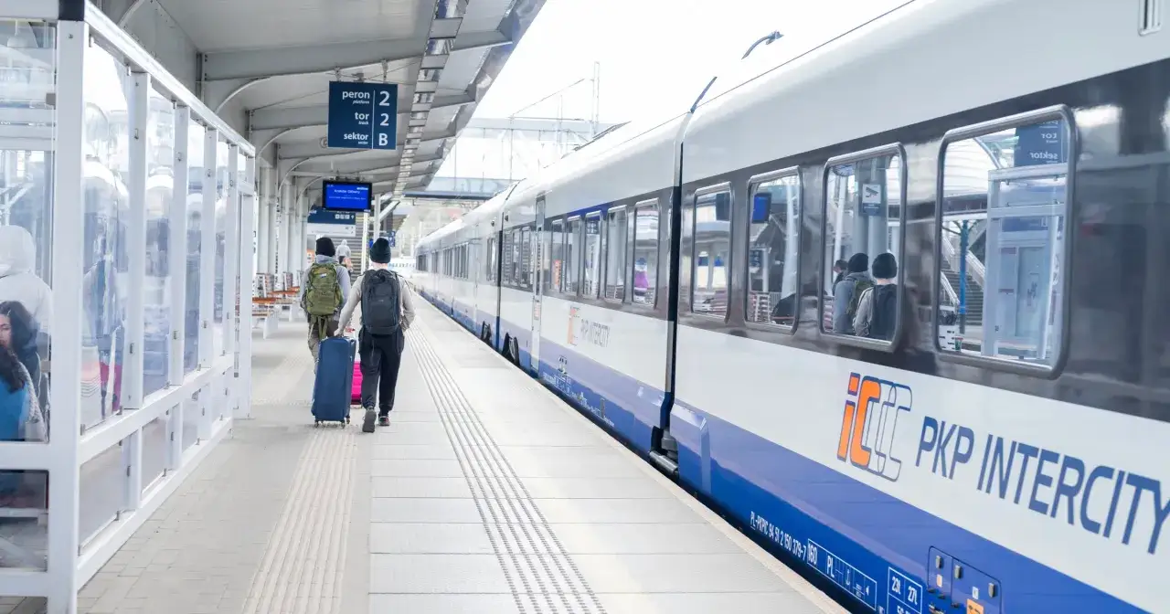 Dwaj podróżni z bagażami idą na peron. Taniej z bliskimi regulamin PKP Intercity zachęca do wspólnych podróży.