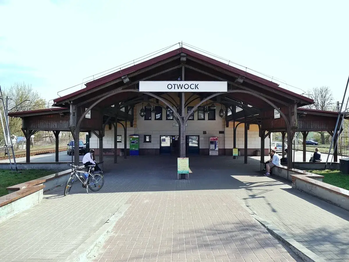 Otwock dworzec PKP. Ludzie czekają na pociąg pod zadaszeniem, rower stoi obok.
