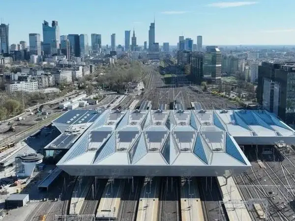 Nowoczesny dach nad peronami największego dworca w Polsce, Warszawy Centralnej, z widokiem na panoramę miasta.